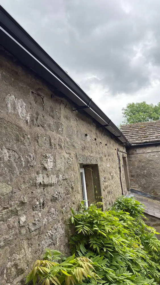 Close view of black aluminium guttering on a stone wall