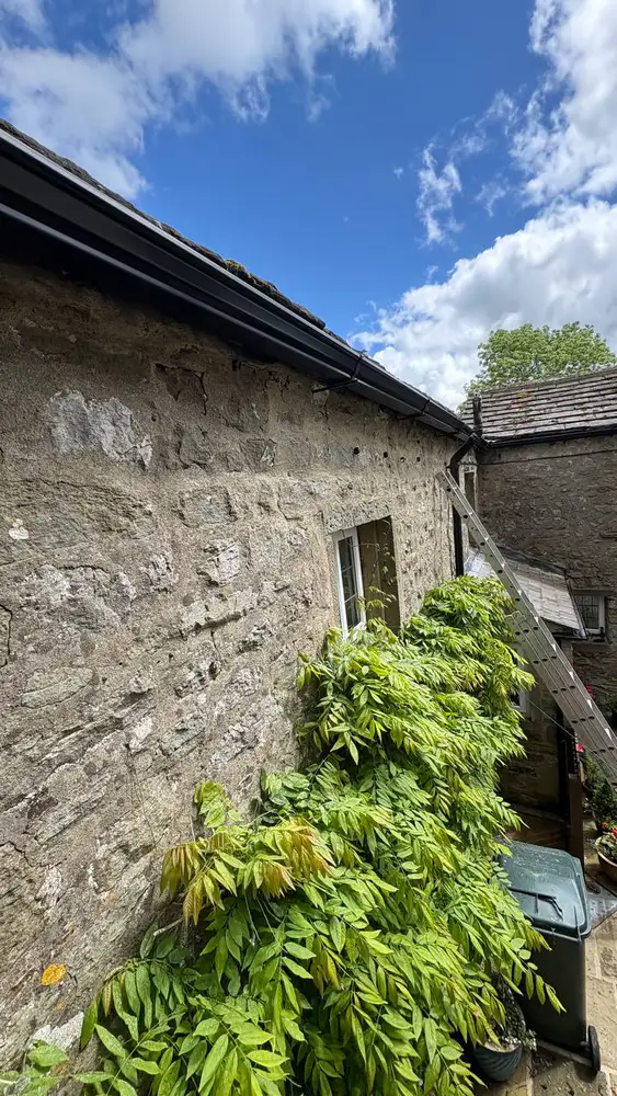Black seamless guttering fitted to a traditional stone house