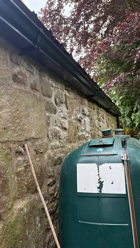 Black guttering installed above an outbuilding oil tank