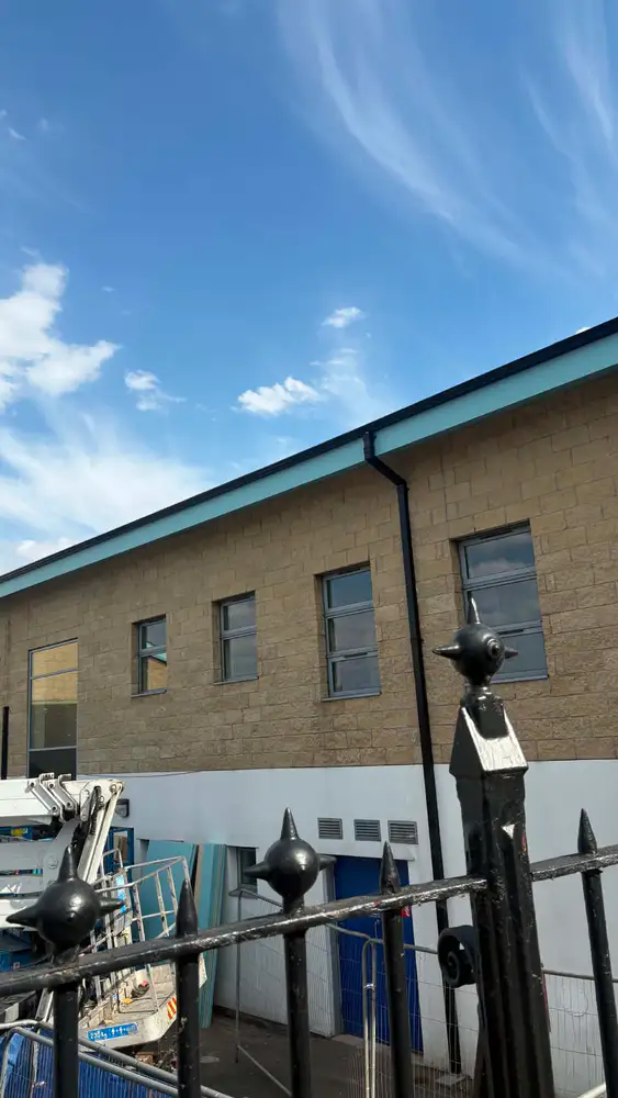 Completed black gutter and downpipe installation on a large commercial building