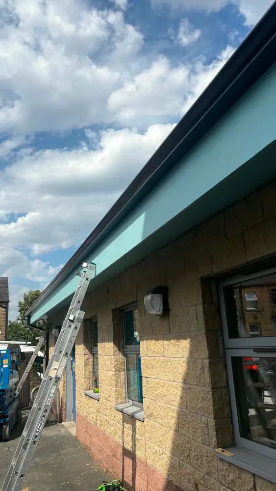 Long black gutter run being finished on a commercial stone building