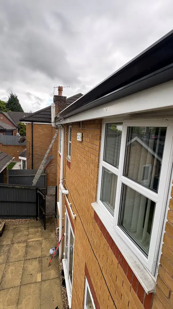 Black gutters and white fascia fitted to a brick house