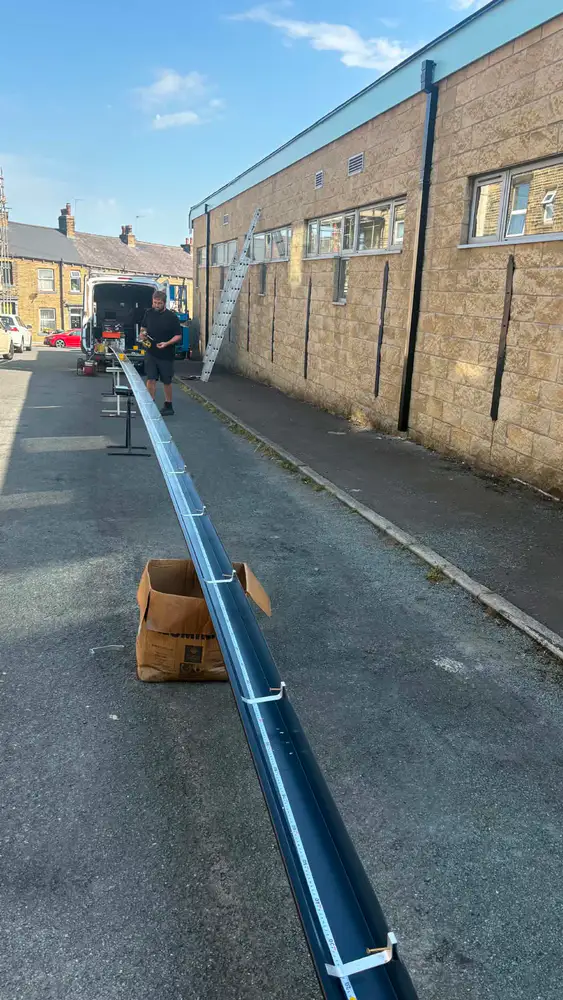 Long seamless aluminium gutter being measured and prepared on site