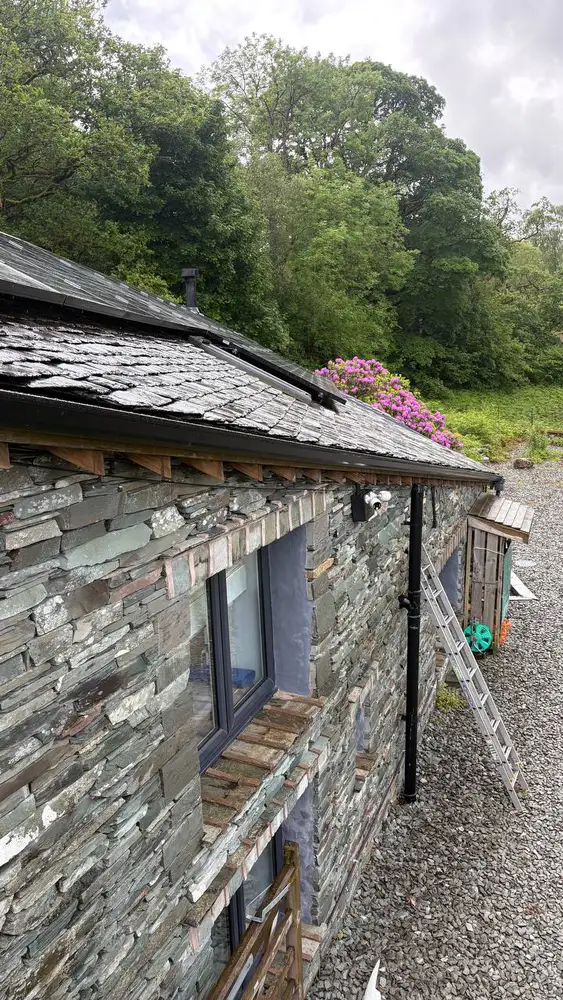 Black seamless guttering fitted below a traditional slate roof