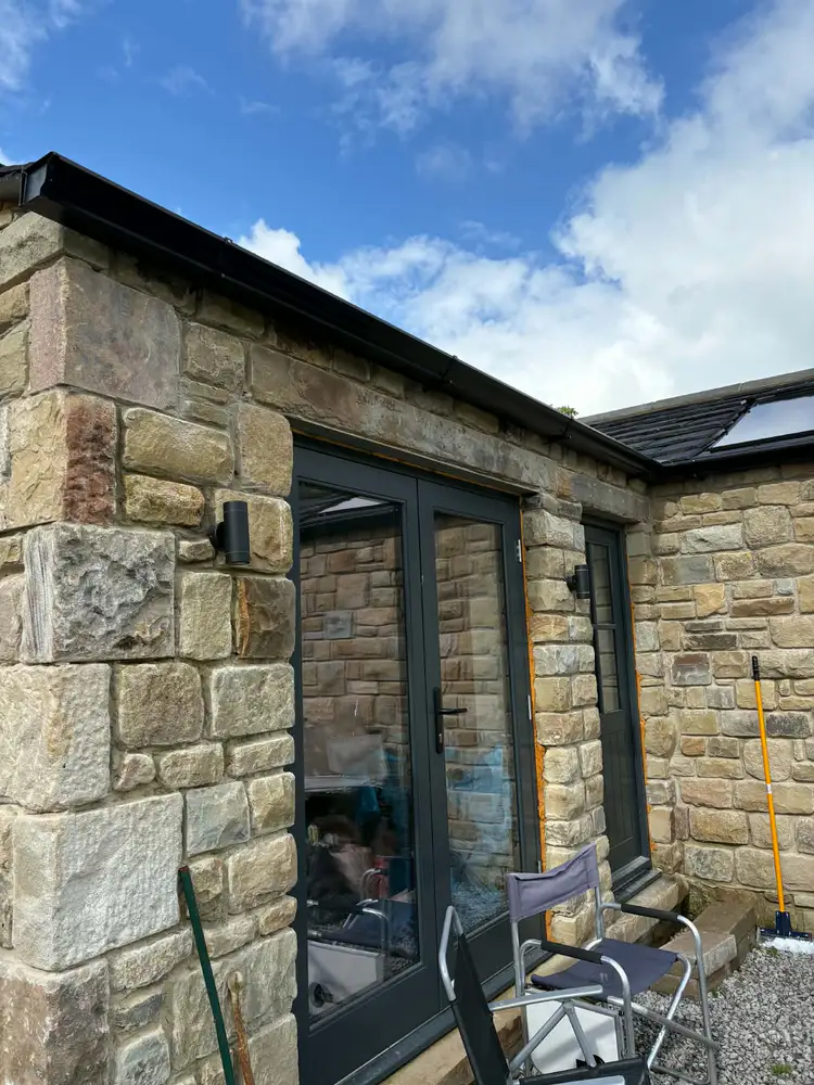 Black guttering following the roofline above doors on a stone extension